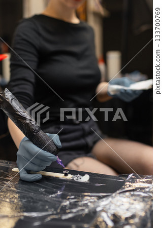 tattoo artist in gloves holding a tattoo machine during a session, preparing tools in a professional studio environment. tattoo artist in gloves holding a tattoo machine during a session, preparing tools in a professional studio environment. 133700769