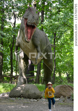 Good leisure for a child. Teaching a child through play. A handsome boy 3 oldl in a yellow jacket excavates the remains of dinosaurs. High quality photo. 133700795
