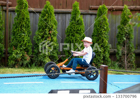 boy driving quad bike, four wheel cycle car, spring brightly morning, sunny day. High quality photo 133700796