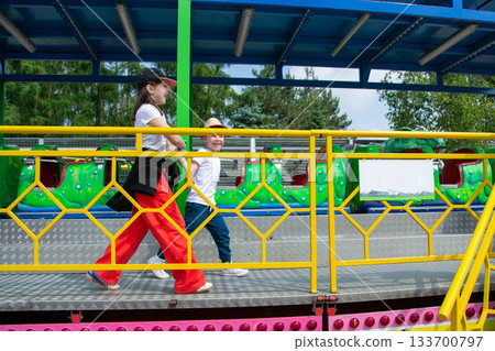 Kids having fun in ferris wheel with chains, carousel ski flyer in amusement park. Happy children, twins having fun outdoors on sunny day. High quality photo 133700797