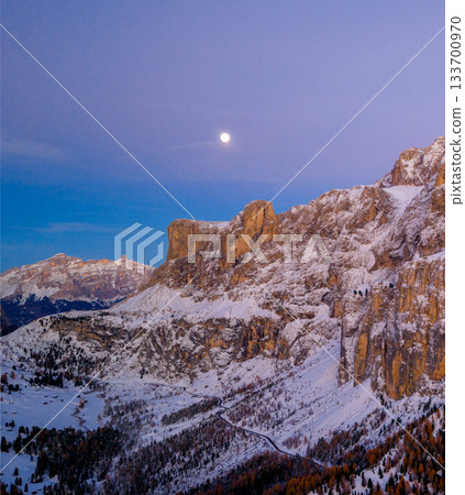 Panoramic view of Dolomite mountain peaks under a glowing full moon. Early winter landscape with snow-covered summits in soft dawn light, captured in high resolution, ideal for large prints. Panoramic view of Dolomite mountain peaks under a glowing full moon. Early winter landscape with snow-covered summits in soft dawn light, captured in high resolution, ideal for large prints. 133700970