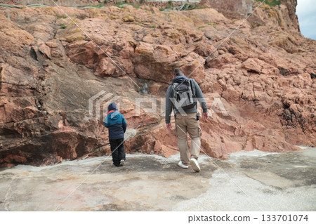 Father and son walking along rocky coastline exploring nature Father and son walking along rocky coastline exploring nature 133701074