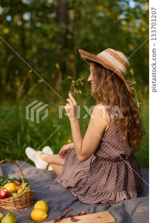 Happy woman savoring fresh fruits on sunny picnic with friends 133701207