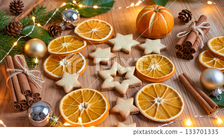 Christmas star cookies and dried orange slices with cinnamon sticks and fir branches on wooden table, holiday composition 133701335