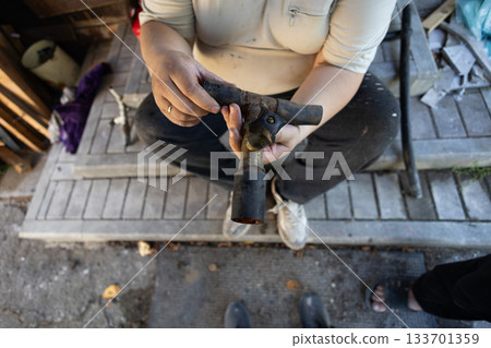 A man holds a complex section of rusty metal water pipe, demonstrating its components and wear, focusing on plumbing repair and maintenance. A demonstration of an old water pipe. 133701359