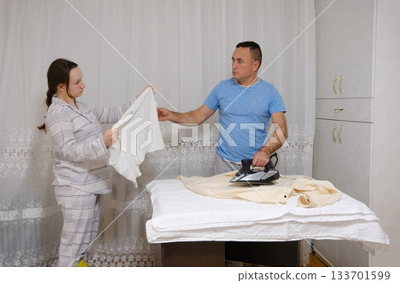 father ironing a shirt And Daughter Ironing Fabric For Sewing With A Steam Iron 133701599