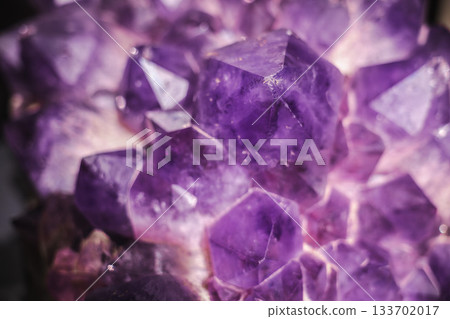 Closeup of deep purple amethyst crystals with sharp geometric facets and rich translucent texture 133702017