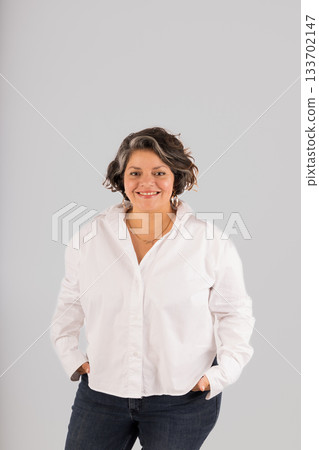A woman is smiling and wearing a white shirt and blue jeans A woman is smiling and wearing a white shirt and blue jeans 133702147