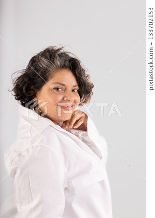 A woman with a white shirt and a gold hoop earring is smiling A woman with a white shirt and a gold hoop earring is smiling 133702153