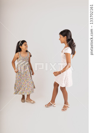 Two young girls are fighting, one of them is wearing a floral dress 133702161