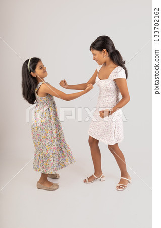 Two young girls are fighting, one of them is wearing a floral dress Two young girls are fighting, one of them is wearing a floral dress 133702162