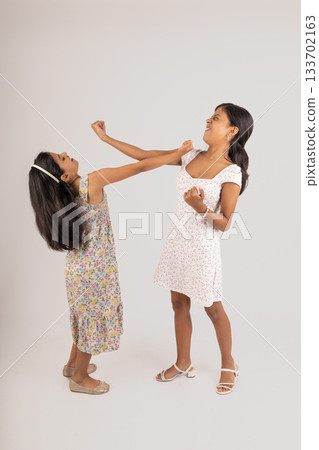 Two young girls are fighting, one of them is wearing a floral dress 133702163