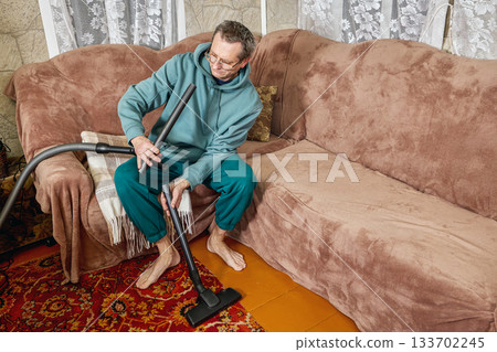 Man cleaning vacuum cleaner hose inside, separating parts for inspection, working on hose maintenance. Man cleaning vacuum cleaner hose inside, separating parts for inspection, working on hose maintenance. 133702245