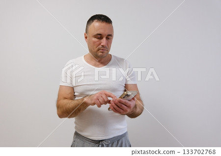 Confused middle aged business man, older professional businessman manager wearing suit using cellphone looking at smartphone reading message on mobile phone standing isolated on white background. 133702768