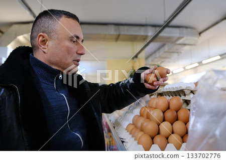 Customer choosing eggs in supermarket, shopping for groceries in refrigerated section Customer choosing eggs in supermarket, shopping for groceries in refrigerated section 133702776
