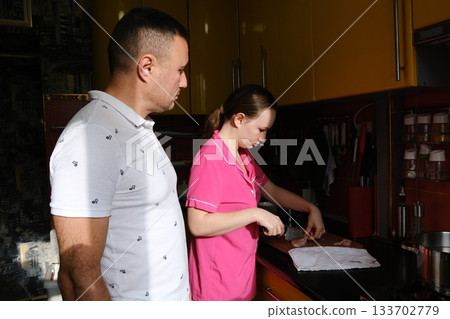 Father and daughter cooking pasta in the kitchen. Family values: dining together at home with family. Yellow kitchen. Modern interior. 133702779
