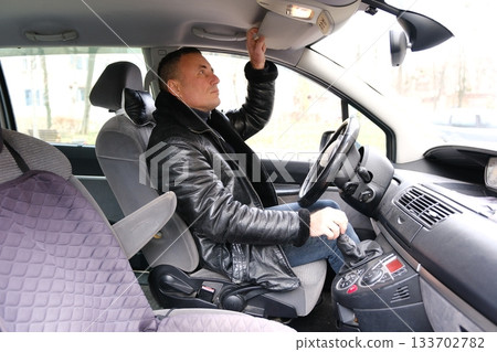The man looks after the car from all sides, opens the doors and gets into it. man polishes a black car with a polisher The man looks after the car from all sides, opens the doors and gets into it. man polishes a black car with a polisher 133702782