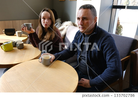 Father and daughter in a cafe drinking tea, talking, spending time with their daughter, family, good relationship, adolescence, teenage girl 133702786