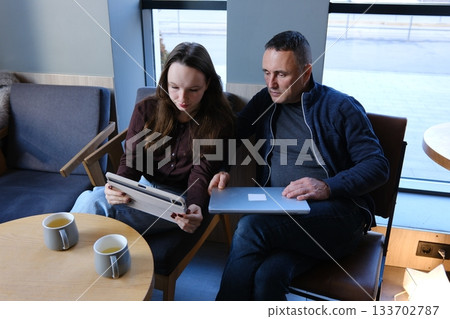 Father and daughter New Generation Female designer standing with her colleague and using a tablet. Happy business people working together in an office. Father and daughter New Generation Female designer standing with her colleague and using a tablet. Happy business people working together in an office. 133702787