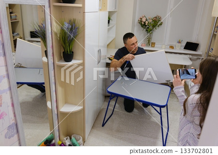 A father repairs a closet door in his daughter's room. Family values: good parent-child relationships. A video set showing the process of repairing a cabinet door A father repairs a closet door in his daughter's room. Family values: good parent-child relationships. A video set showing the process of repairing a cabinet door 133702801