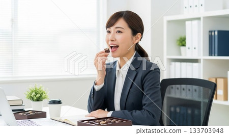 一位日本女員工在休息時享用巧克力 一位日本女員工在休息時享用巧克力 133703948