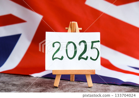 Paper note with text 2025 on National symbol of Great Britain. British wave the UK silky flag background. Financial outlook planning, new year annual report 133704024