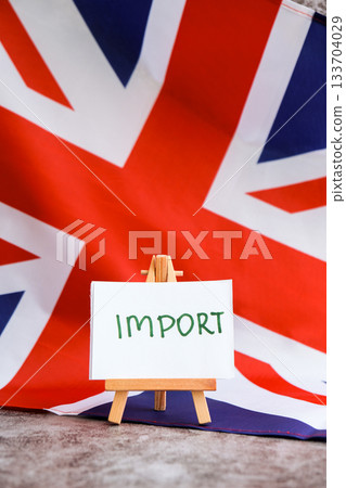 Paper note with words IMPORT on National symbol of Great Britain. British wave the UK silky flag background. Economy industry global market international shipping 133704029