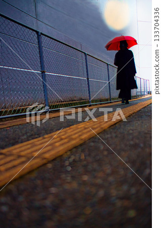 A woman walking down a back alley in the city on a rainy day A woman walking down a back alley in the city on a rainy day 133704336