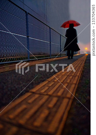 A woman with an umbrella walking on a sidewalk on a rainy day 133704365