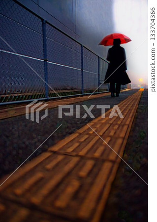 A woman with an umbrella walking on a sidewalk on a rainy day A woman with an umbrella walking on a sidewalk on a rainy day 133704366