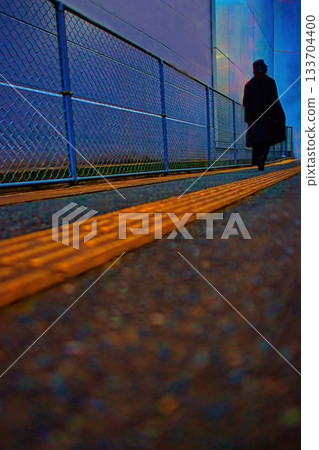 A woman in a black coat walking down a back alley in the city A woman in a black coat walking down a back alley in the city 133704400