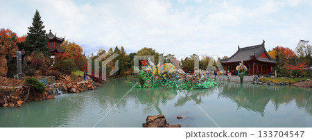Chinese Garden with waterfall and colorful figurines reflected on water, Chinese Pavilion and Stadium tower Chinese Garden with waterfall and colorful figurines reflected on water, Chinese Pavilion and Stadium tower 133704547