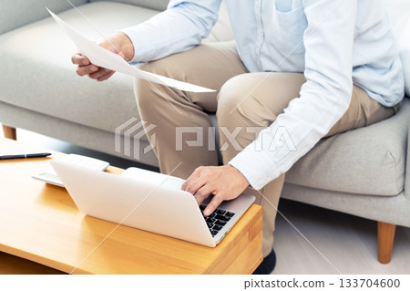 A middle-aged man operating a computer in the living room 133704600