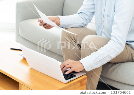 A middle-aged man operating a computer in the living room 133704601