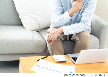 A middle-aged man operating a computer in the living room A middle-aged man operating a computer in the living room 133704611
