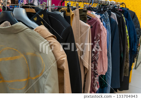 Clothes on hangers during a clothing swap event promoting sustainable fashion and reuse. Eco-friendly lifestyle, recycling, and circular economy concept encouraging people to exchange pre-loved 133704943