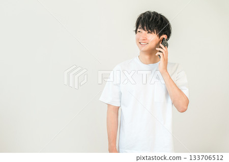 一位年輕的亞裔男子正在用他的智慧型手機打電話 133706512