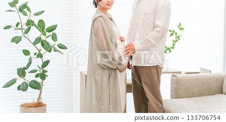 A couple and a pregnant woman in the living room of their home A couple and a pregnant woman in the living room of their home 133706754