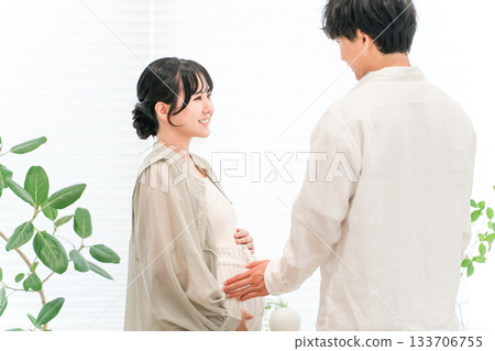 A couple and a pregnant woman in the living room of their home A couple and a pregnant woman in the living room of their home 133706755