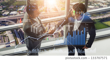 Business professionals shaking hands in office with financial graphs and charts representing market trends and growth from a high-rise building view Scalp Business professionals shaking hands in office with financial graphs and charts representing market trends and growth from a high-rise building view Scalp 133707571