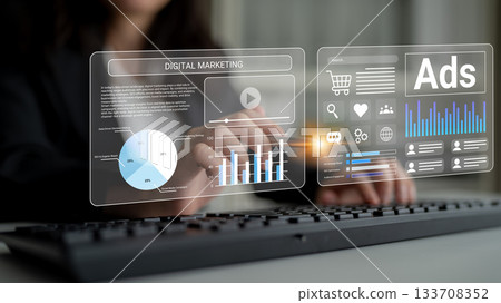 Focused professional working with futuristic digital marketing tools, analyzing data through holographic interface and keyboard in modern office setting Gantry 133708352
