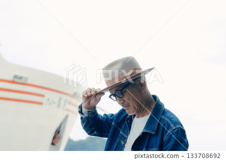 Portrait of a senior man enjoying a trip while looking at the ship Portrait of a senior man enjoying a trip while looking at the ship 133708692