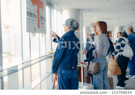 A senior couple and passengers traveling through the terminal corridor 133708834
