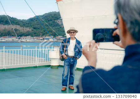 Travel portrait of a senior couple looking at the port town on the deck of a ferry Travel portrait of a senior couple looking at the port town on the deck of a ferry 133709040