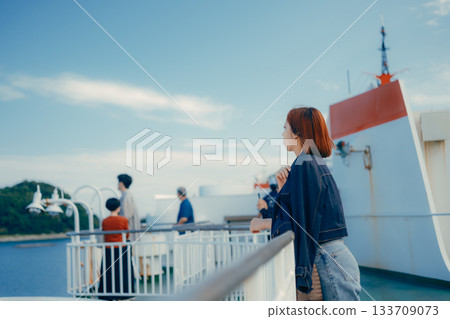 Travel scene of a woman in her twenties looking at the sea on the deck of a ferry Travel scene of a woman in her twenties looking at the sea on the deck of a ferry 133709073