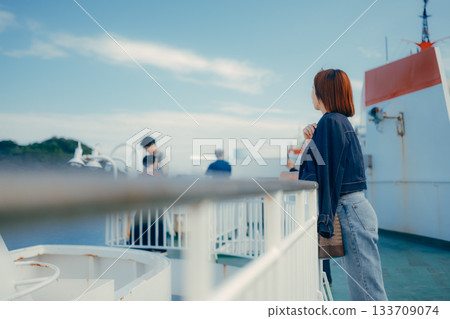 Travel scene of a woman in her twenties looking at the sea on the deck of a ferry 133709074