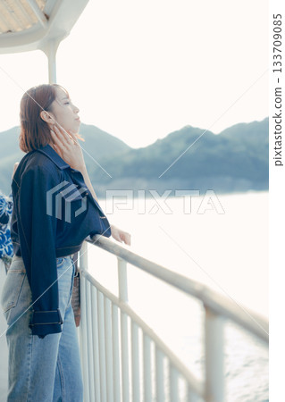Travel scene of a woman in her twenties looking at the sea on the deck of a ferry Travel scene of a woman in her twenties looking at the sea on the deck of a ferry 133709085
