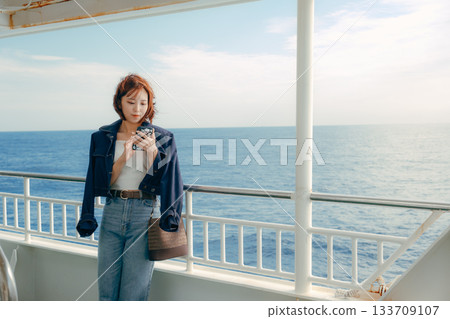 旅行場景:一位二十多歲的女子在渡輪甲板上感受海風。 旅行場景:一位二十多歲的女子在渡輪甲板上感受海風。 133709107