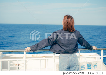 Travel scene of a woman in her twenties feeling the sea breeze on the deck of a ferry 133709111
