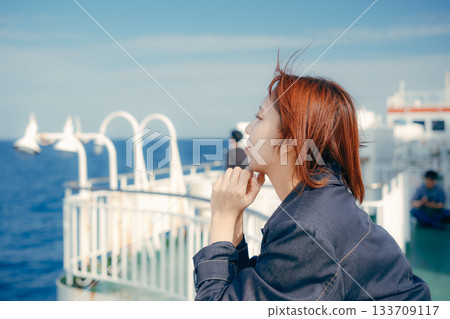 旅行場景:一位二十多歲的女子在渡輪甲板上感受海風。 旅行場景:一位二十多歲的女子在渡輪甲板上感受海風。 133709117